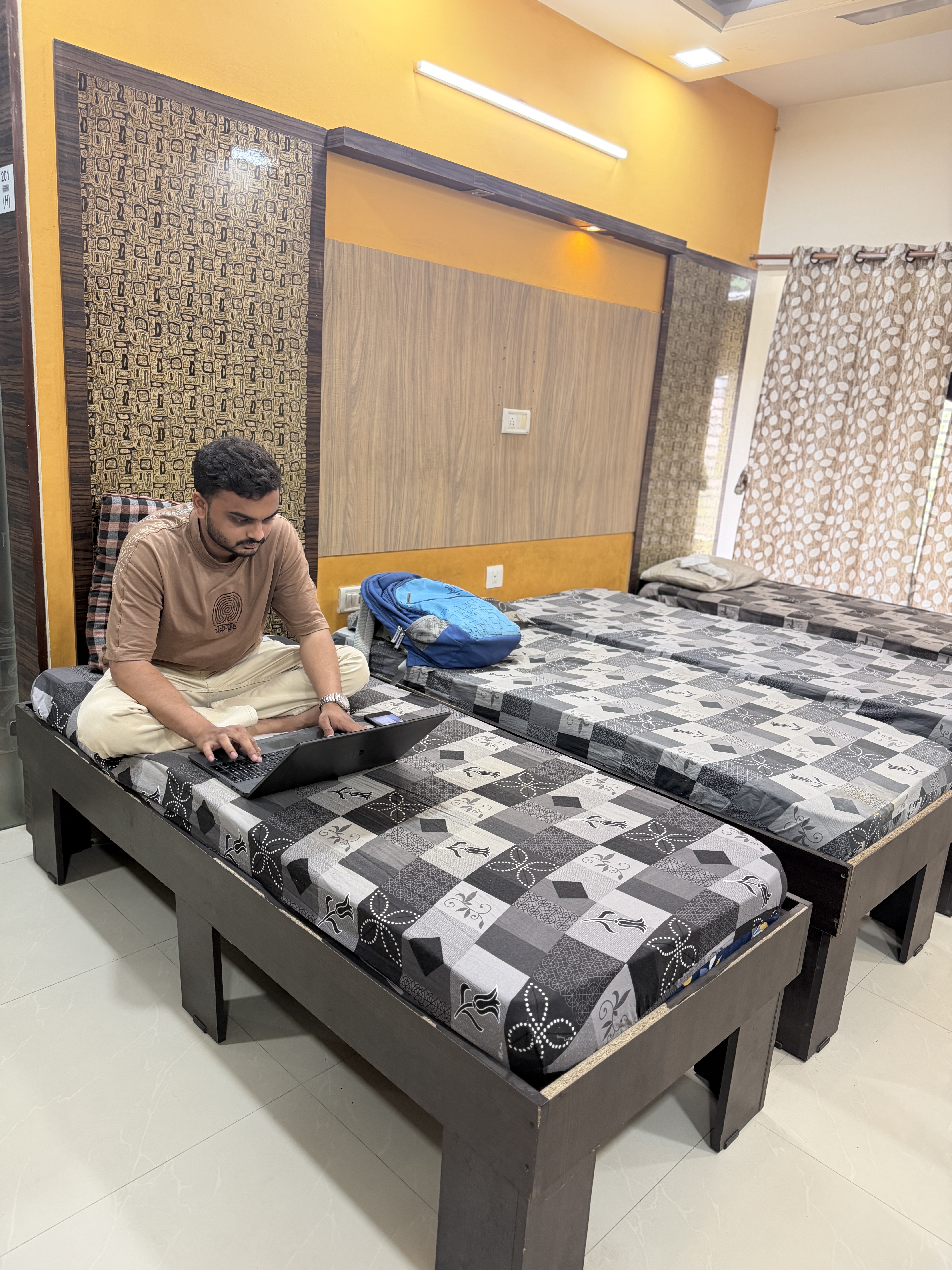 Resident studying on laptop in his room, Ansh Boys PG
